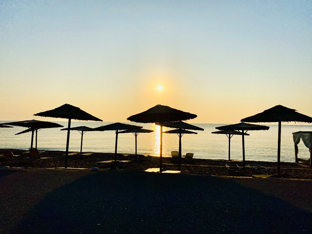 Strohschirme am Strand von Rhodos bei Sonnenuntergang